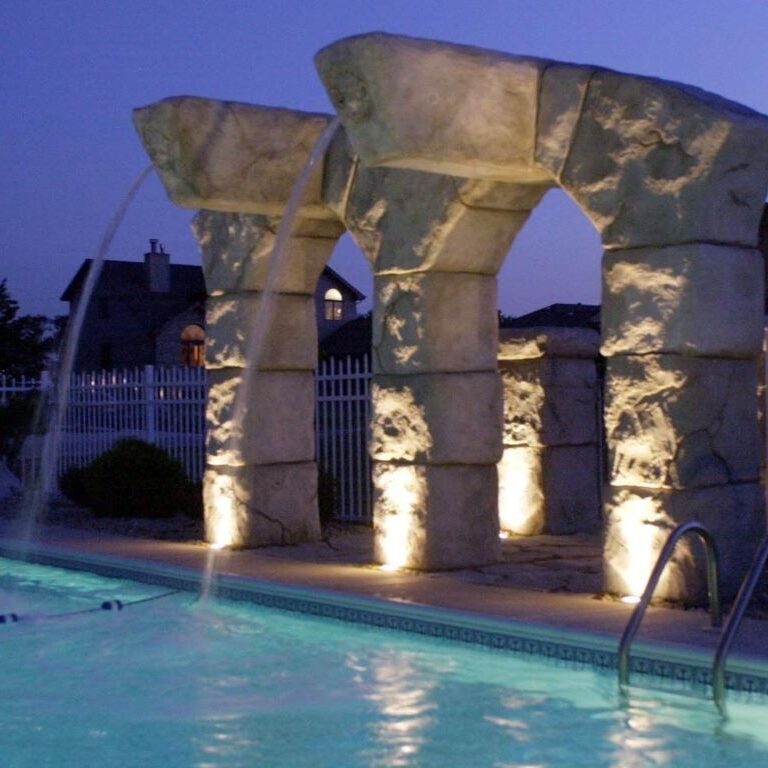 Image a water feature made of two vertical towers. You can see th e water going into the swimming pool.